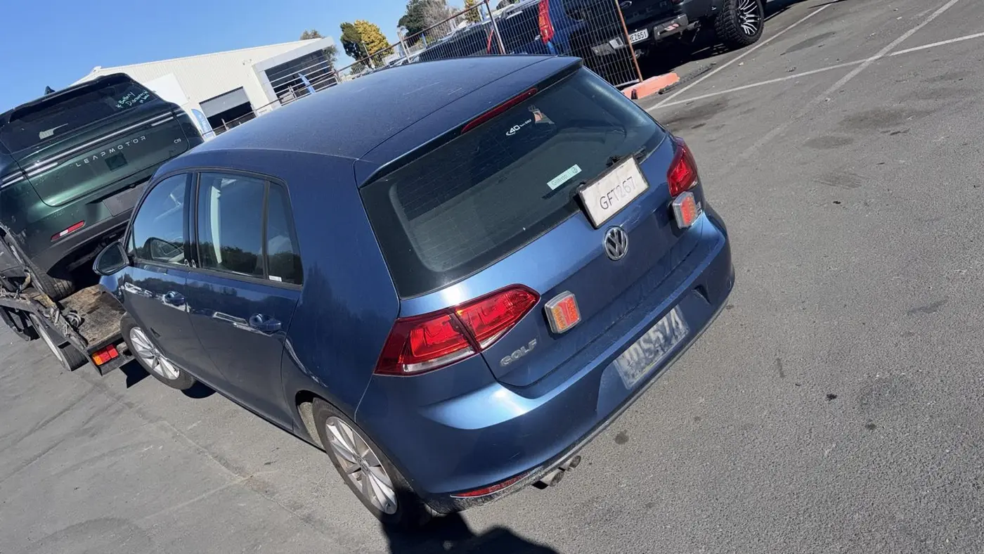 Blue VW hatchback on a tow truck