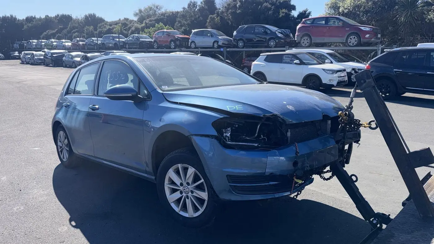 Non-running blue hatchback being winched onto a tow truck