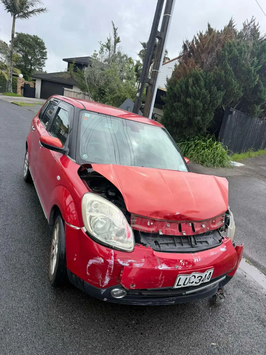 Written-off red hatchback with heavy front-end damage