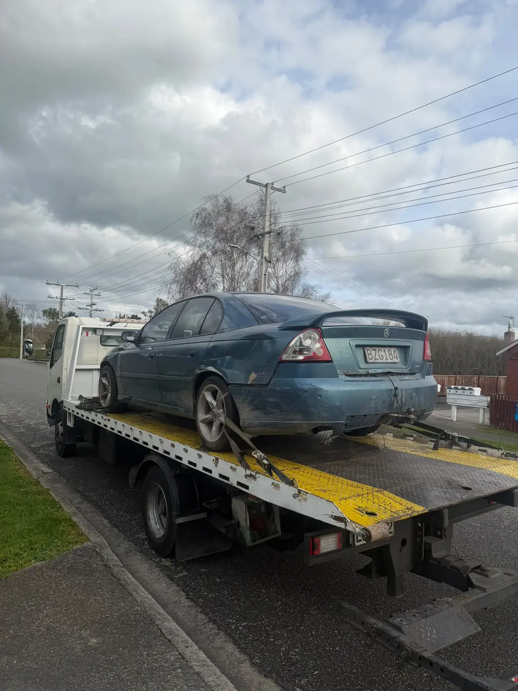 Blue sedan on a flatbed tow truck